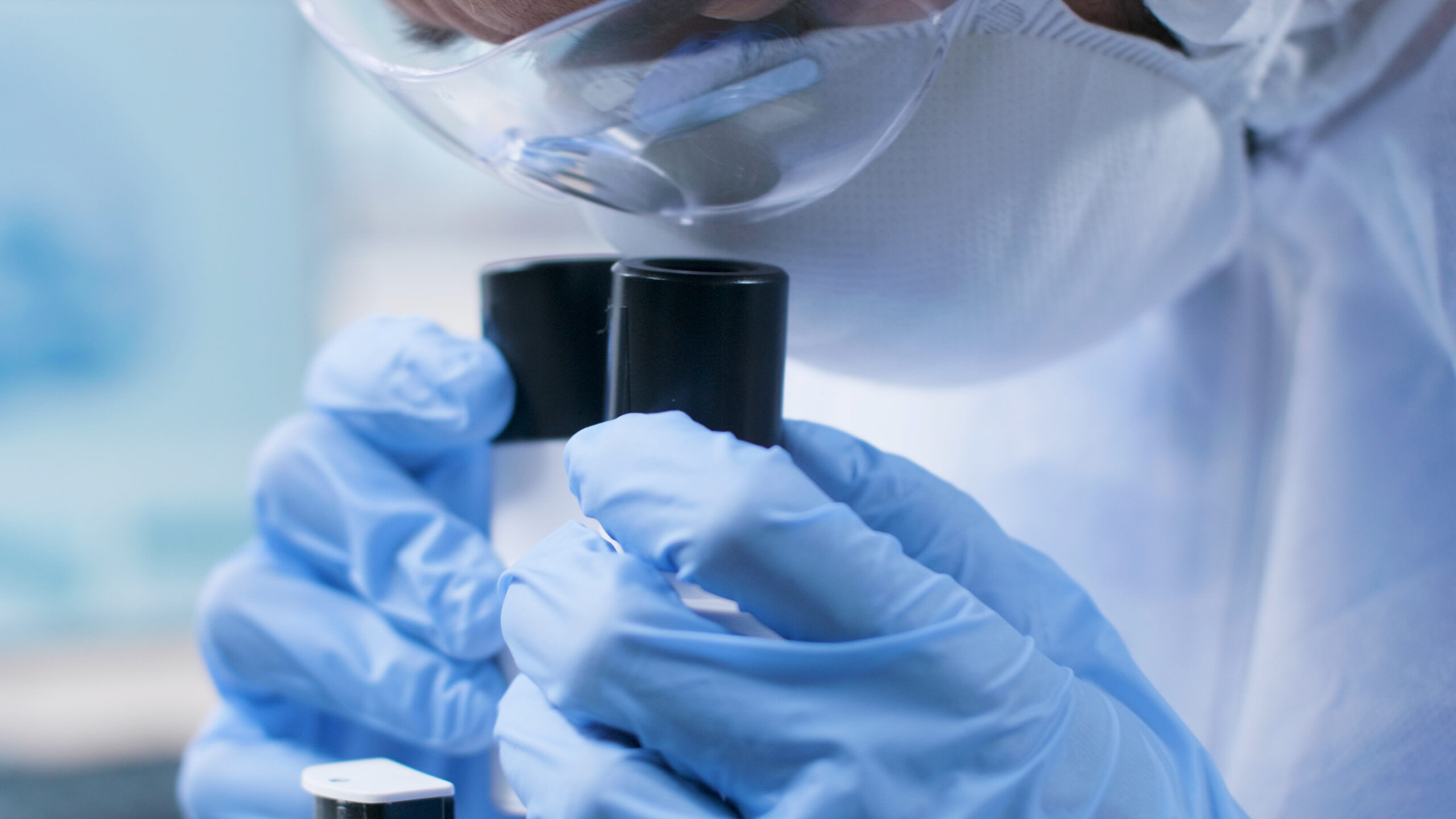 Close-up of a scientist or researcher in the pharmaceutical industry looking into a medical microscope, analyzing a sample for quality control in research and development.